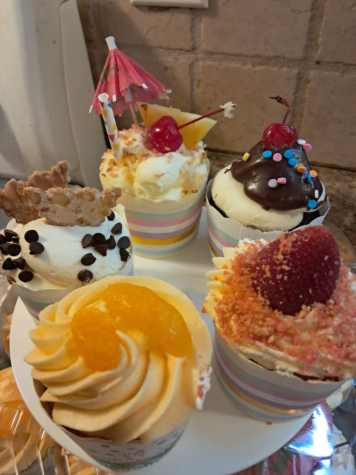 Assorted specialty cupcakes with fruit and candy toppings