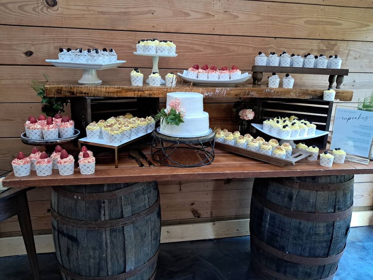 Cupcake display with a small cake centerpiece on a rustic table